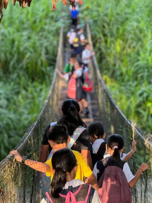 Children crossing a suspension bridge on their journey to school in rural Sabah